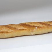 A baguette resting on a white surface, showcasing its long shape and crusty exterior