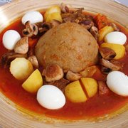 A plate of Bazin (center) served with a stew and whole hard-boiled eggs